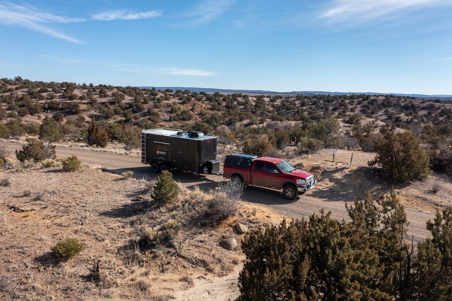 A truck towing an off road camper through the wilderness.