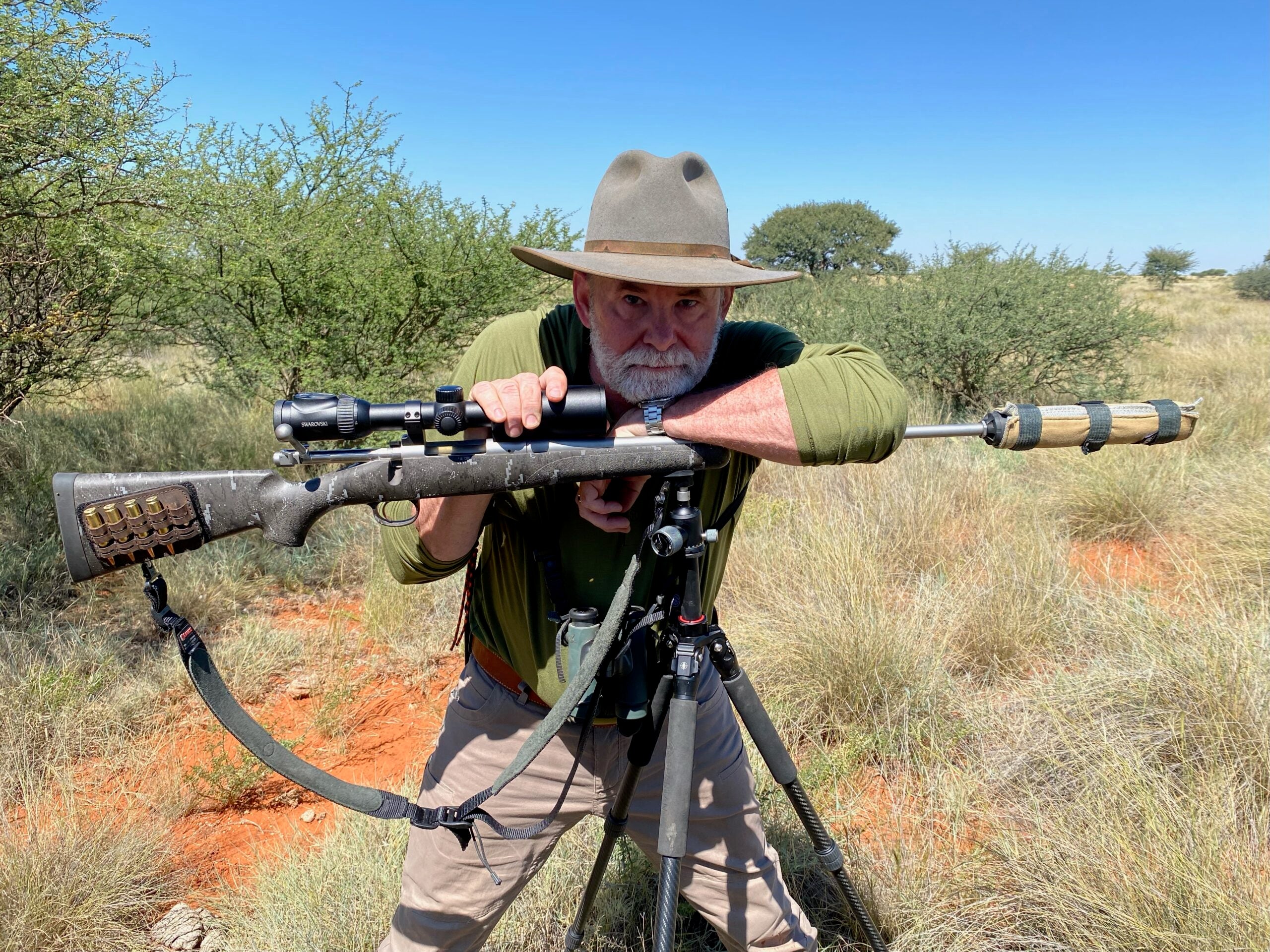 Man leaning on a rifle and tripod.