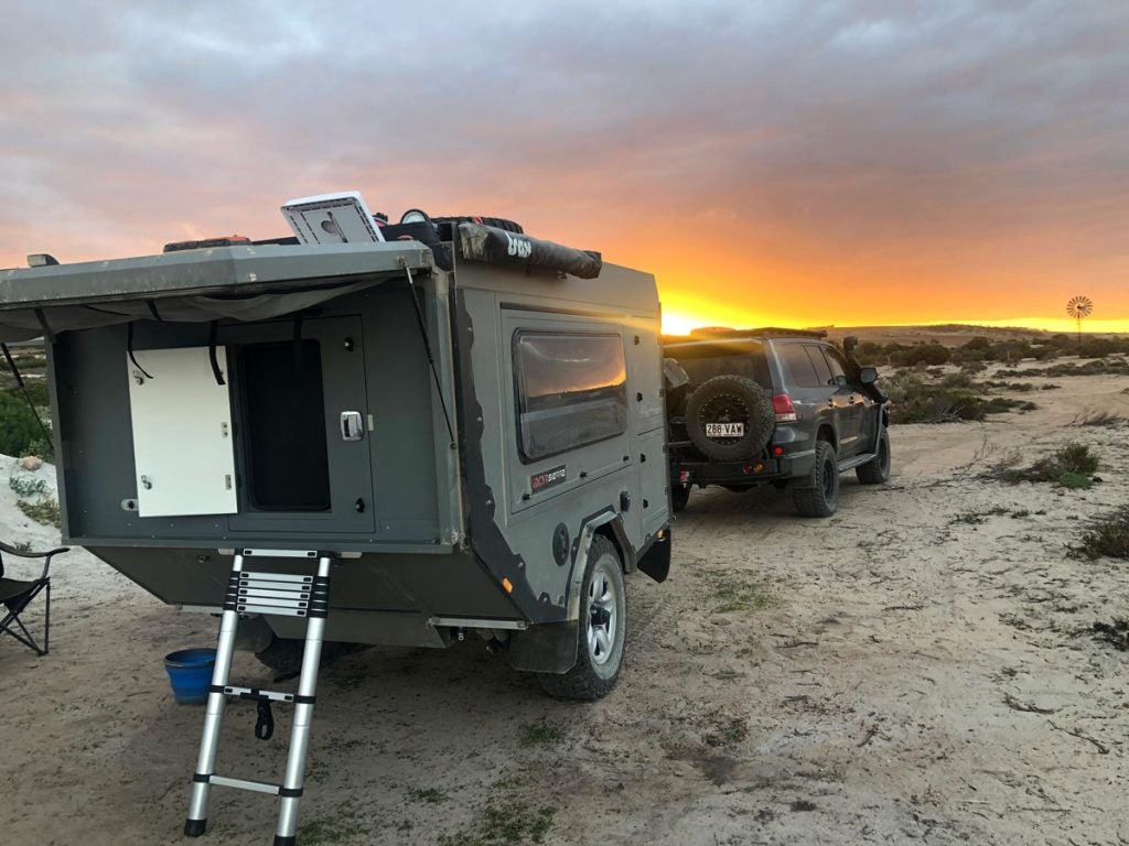 A truck with a trailer on the beach.