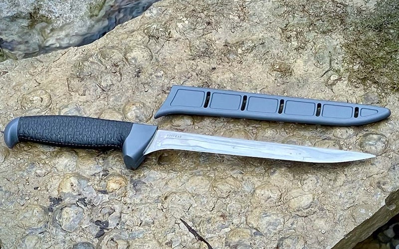 A best fillet knife with a black handle next to a silver sheath