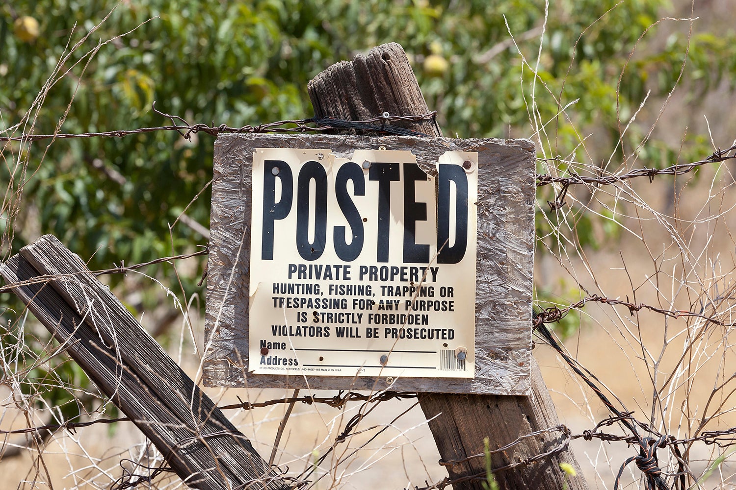 posted sign on collapsing wood fence