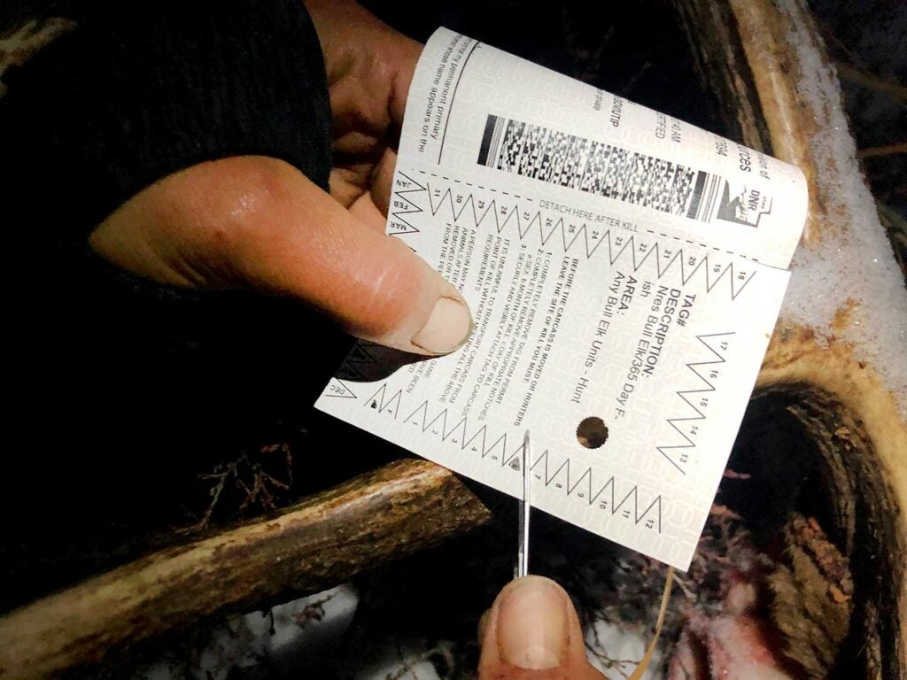 A hunter puts a notch in a hunting tag.