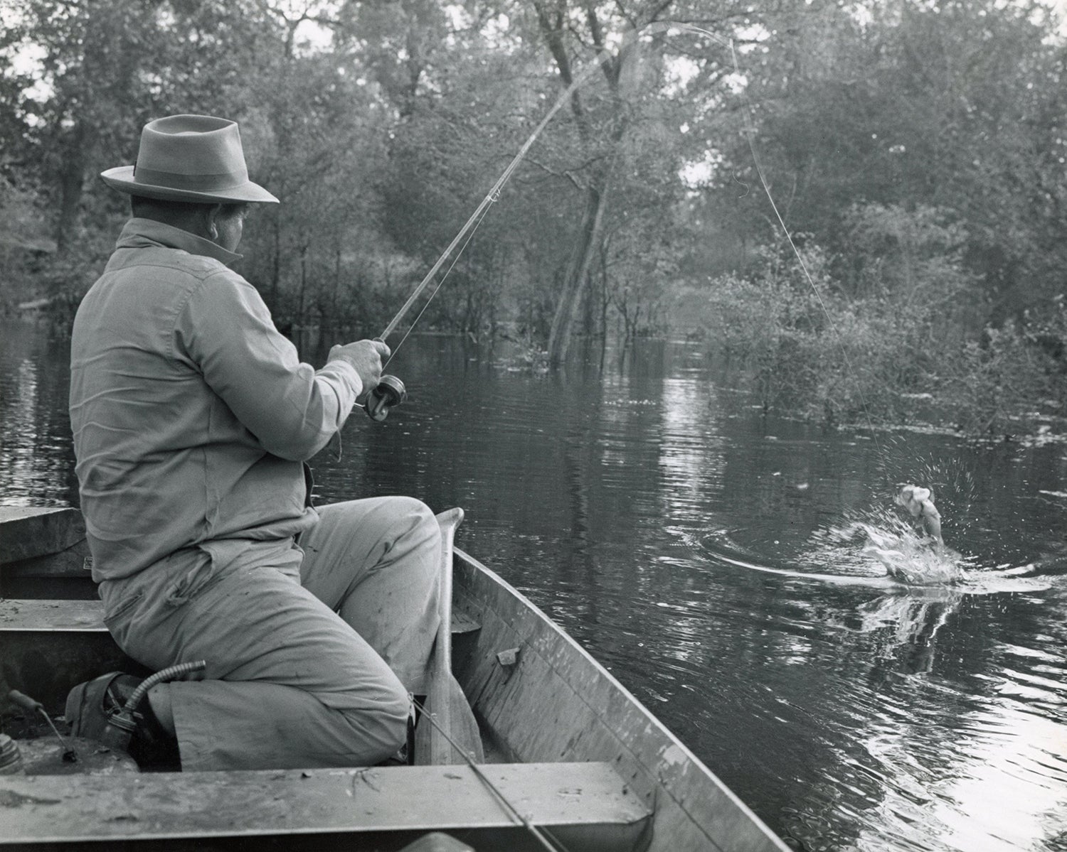 Angler fights fish from old-looking boat with old-style gas can behind him