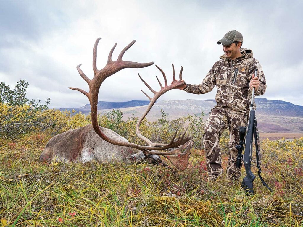 Alex Robinson standing by an alaskan caribou