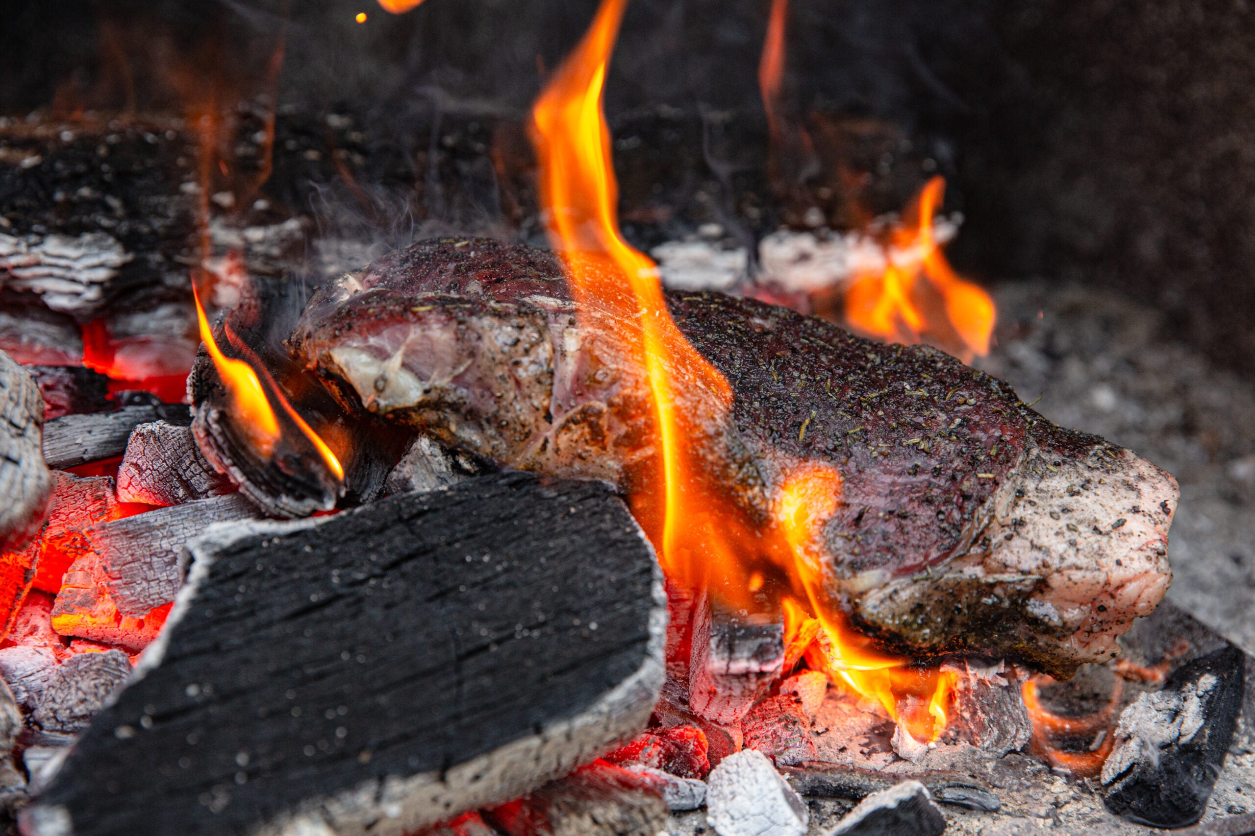 steak being cooked directly on coals