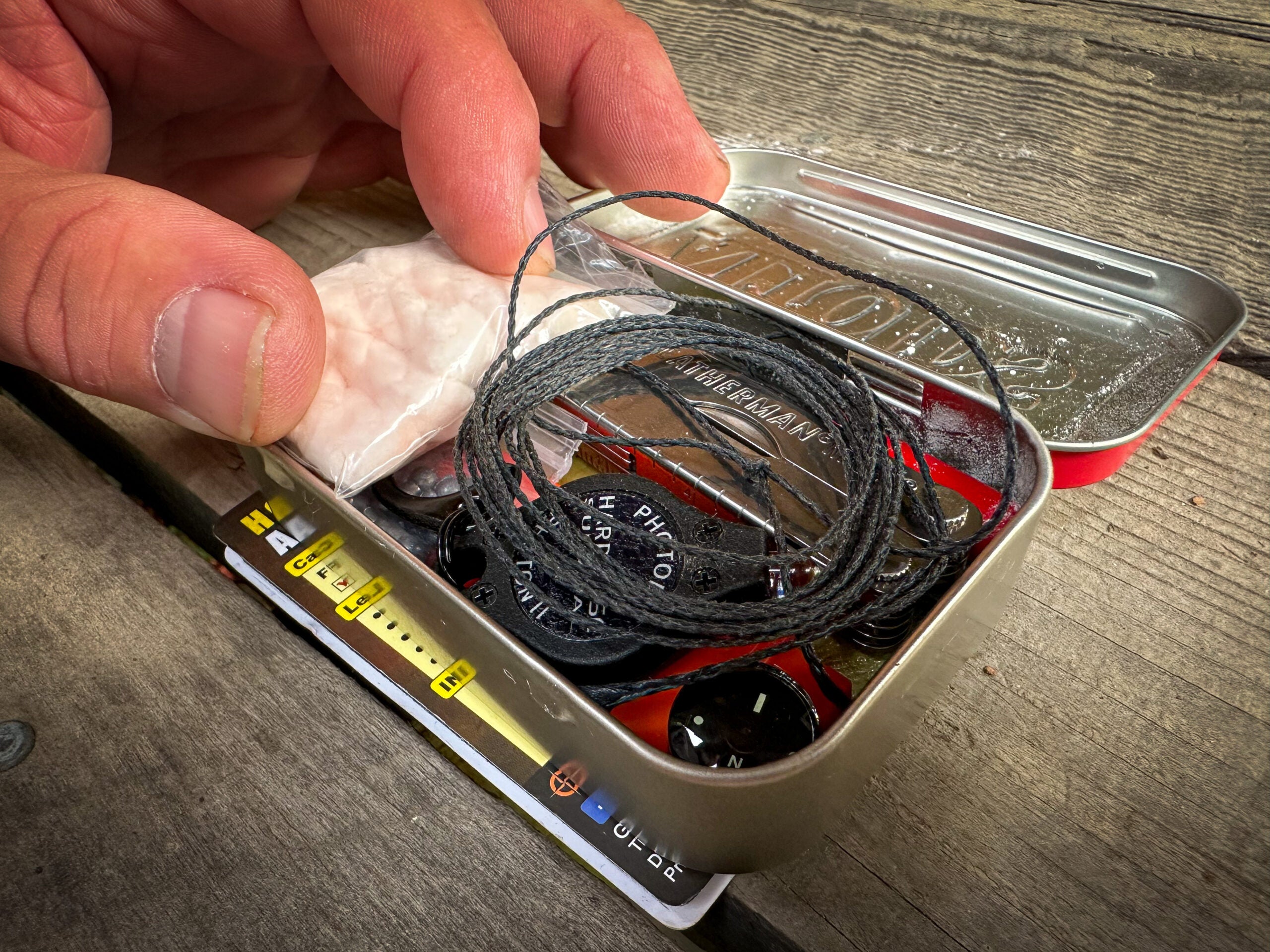 placing survival gear into a small survival kit