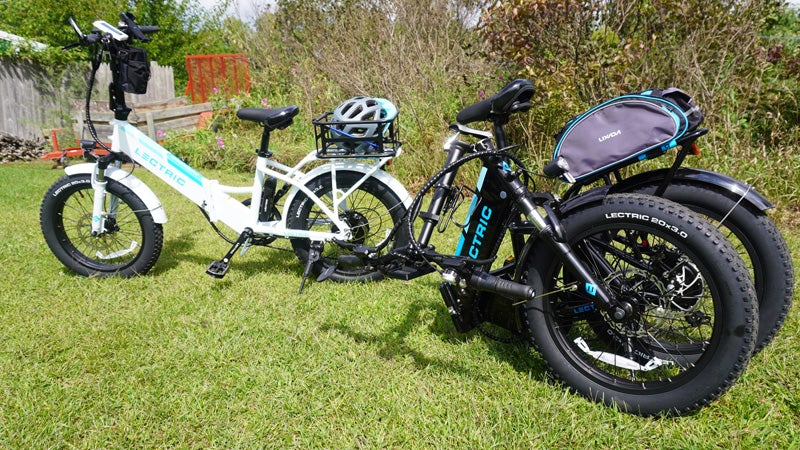 The black and white versions of the Lectric 3.0 bike, one folded, one unfolded on a grassy lawn.