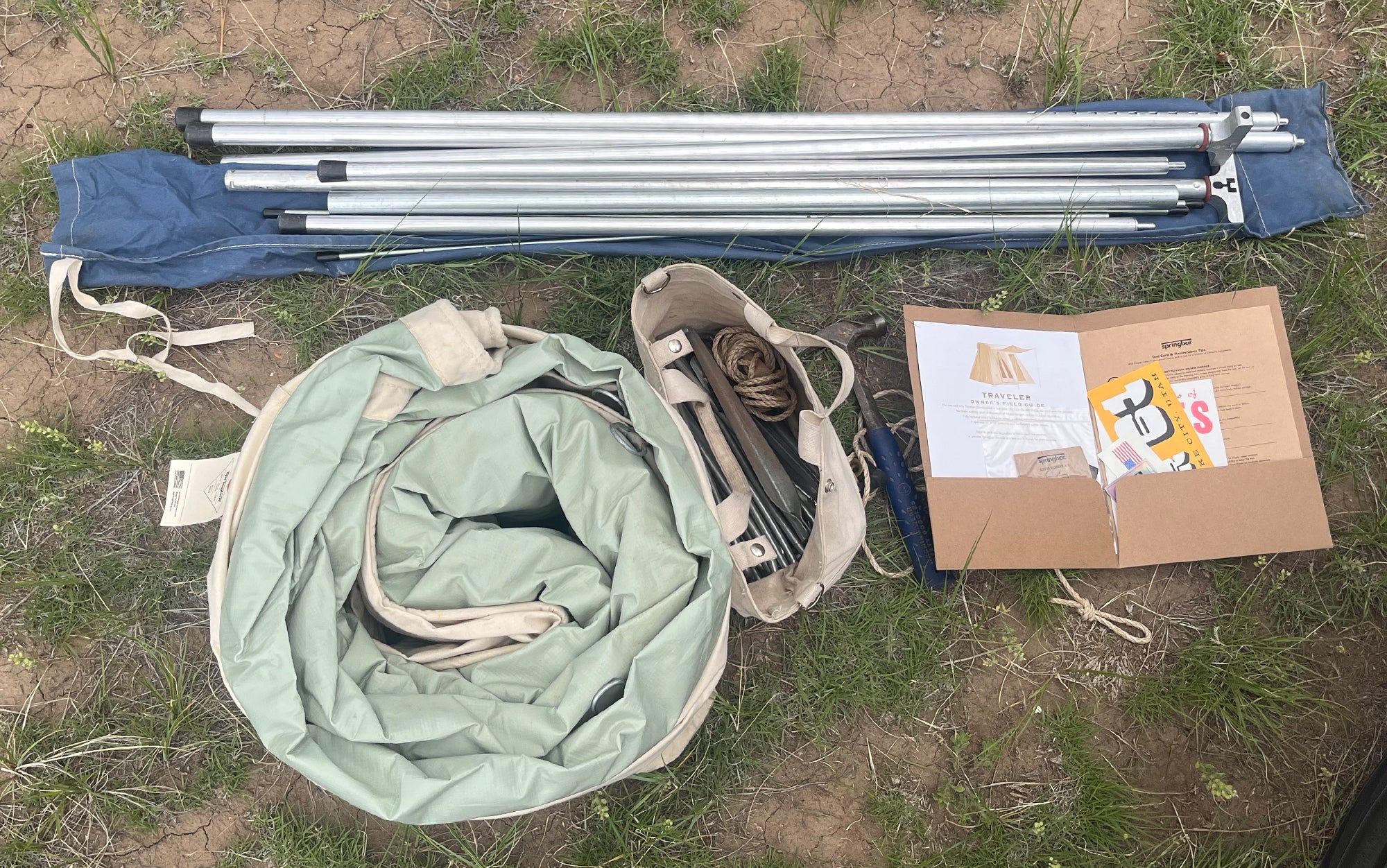 Pictured is the Traveler tent with storage bag, pole set with storage bag, tent stakes in the included canvas bag with awning ropes, the ownerâs field guide, and a hammer.