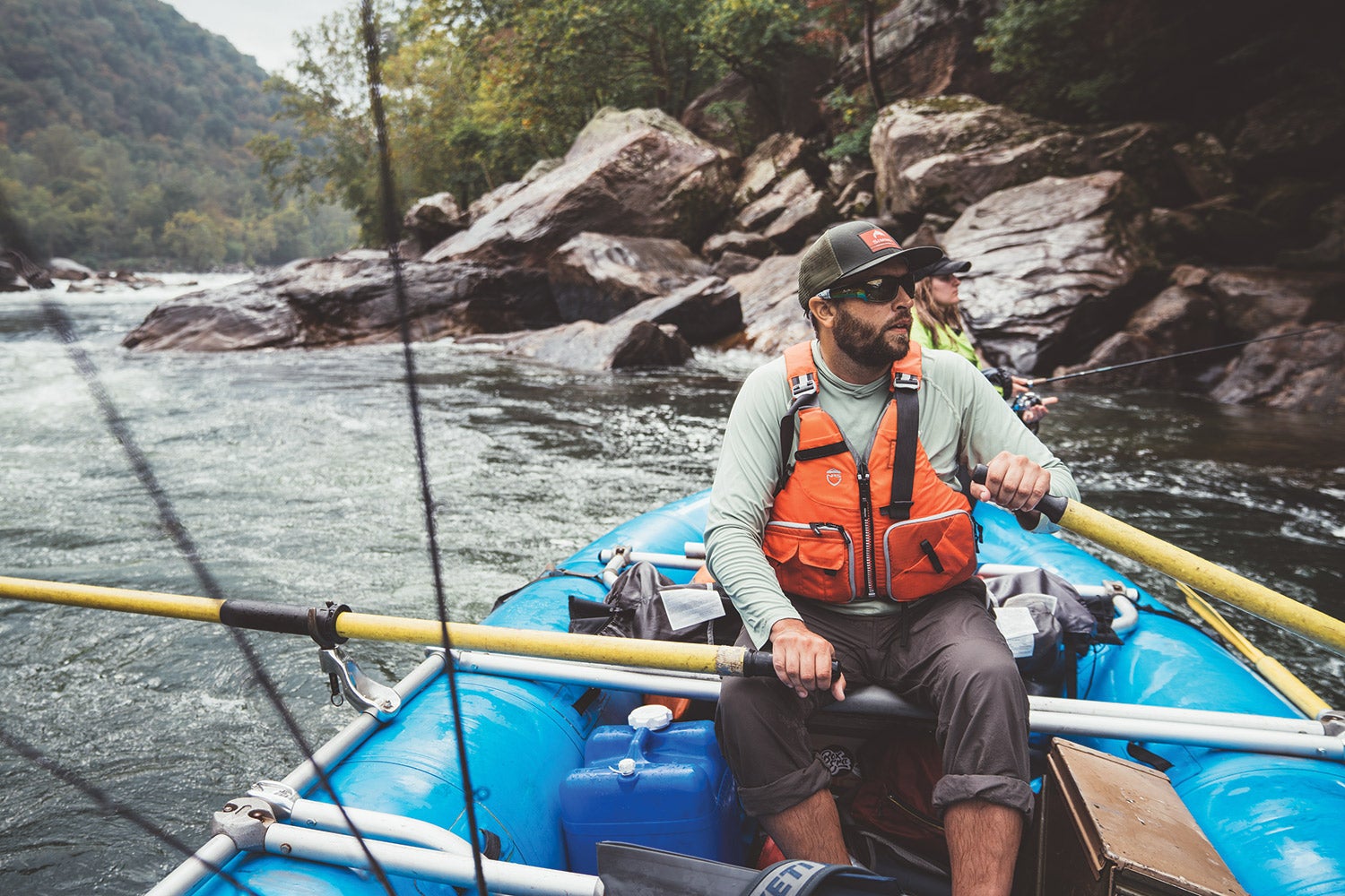 rafter guides boat past rocky riverbank