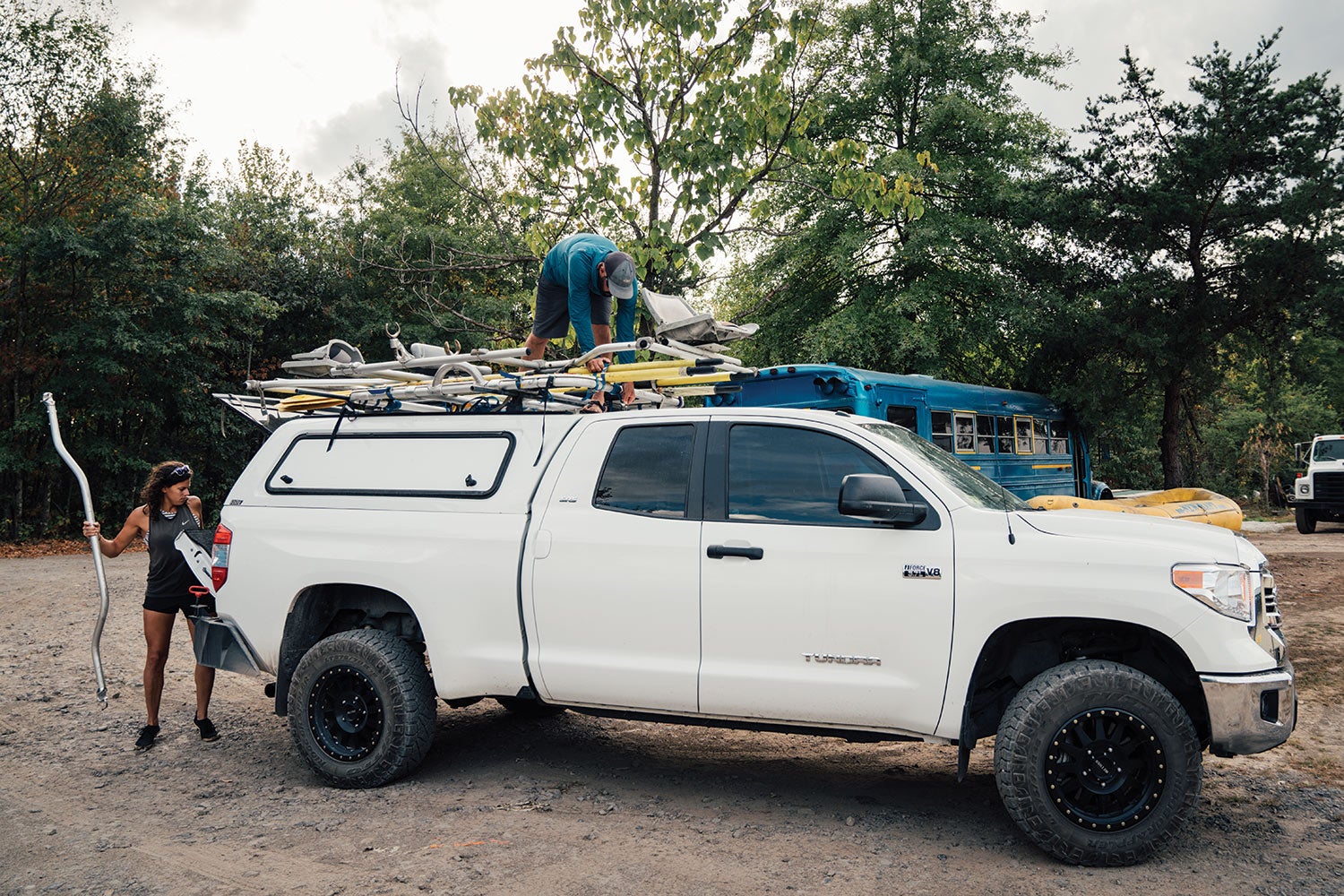 anglers load gear into and onto white truck