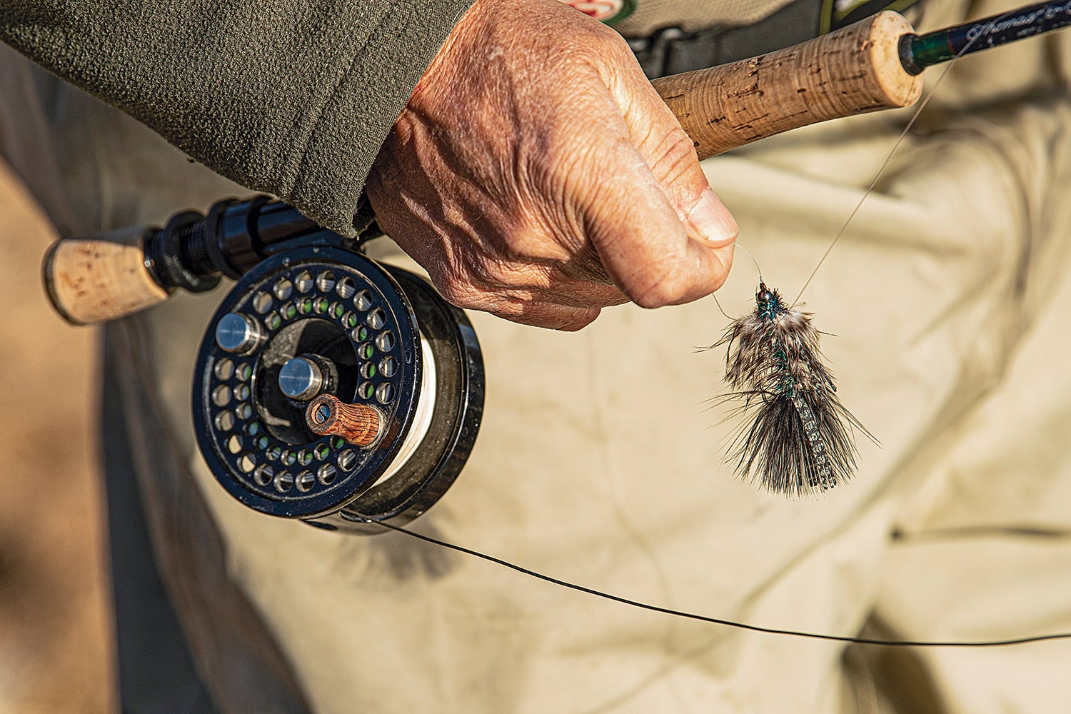 closeup of streamer fly, with hand holding tippet