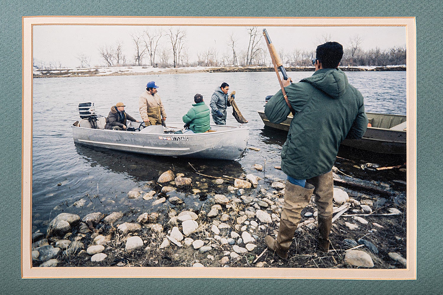 scrapbook photo showing men in boat on river, one man exiting the water, and an armed officer standing on shore