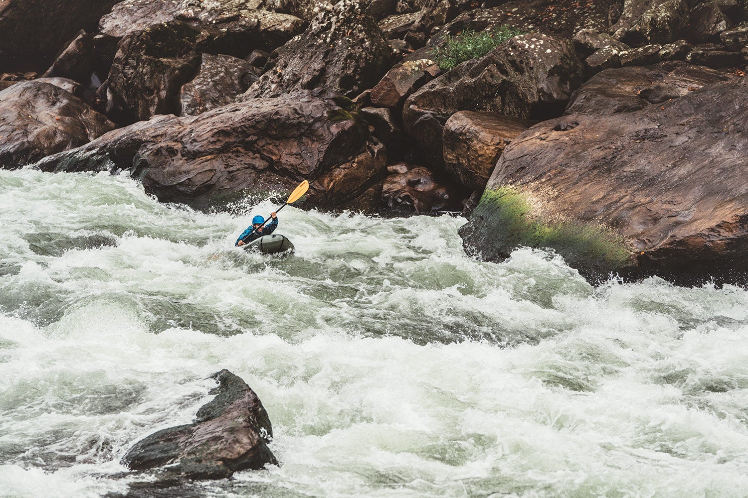 paddler in small packraft travels downriver in white water