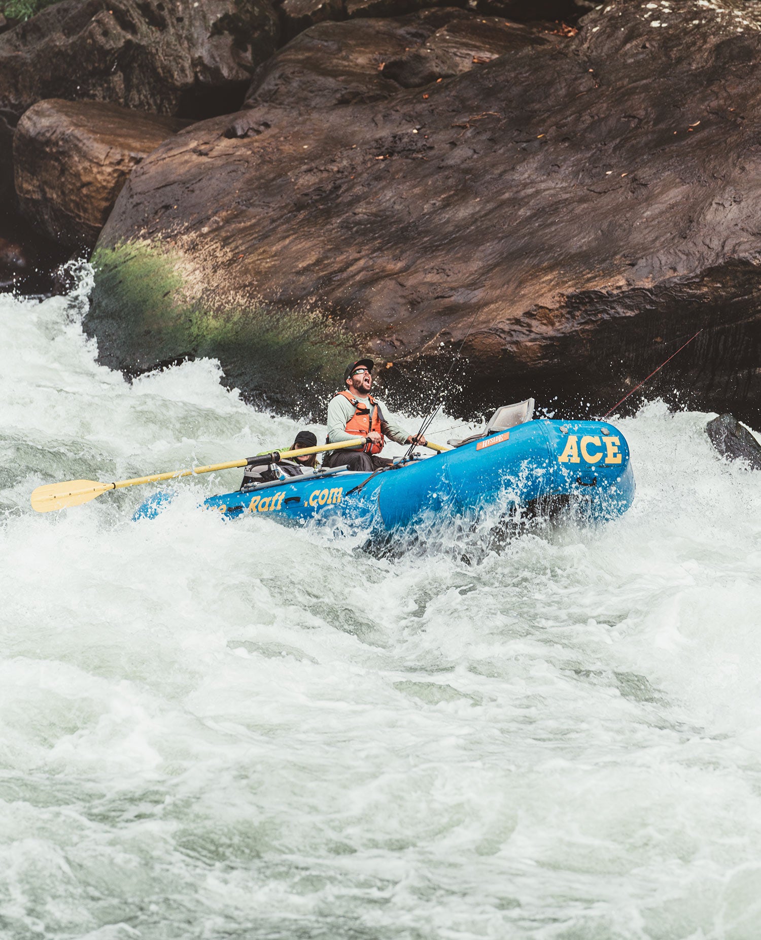 Rafter steers blue raft downriver through rapids.