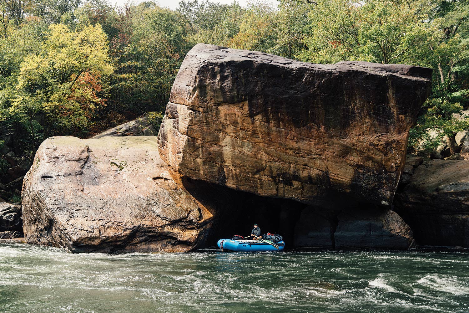 Huge boulders tower over raft and rafter on New River.