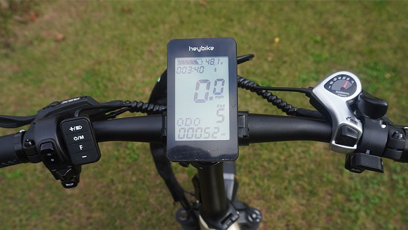 The display screen and controls of the Heybike Ranger S against a green grass background.