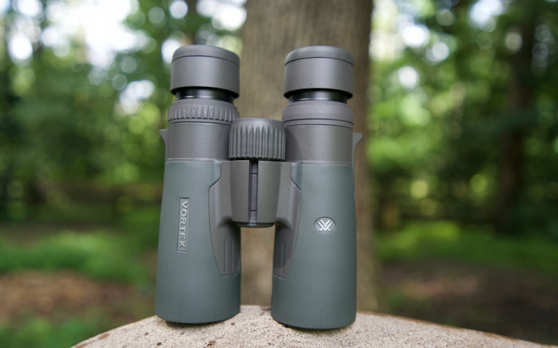 Green binoculars sitting on top of a rock