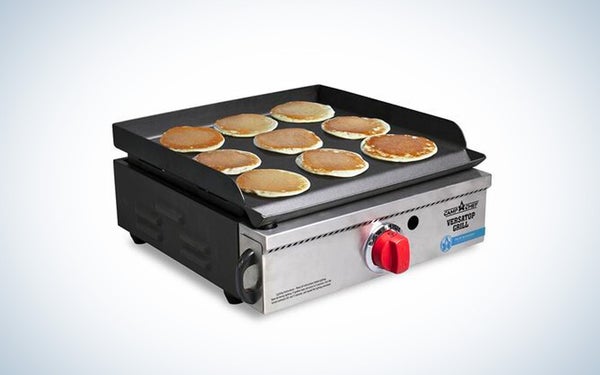 A silver camp chef versatop camp stove cooking pancakes on a black and white gradient background.