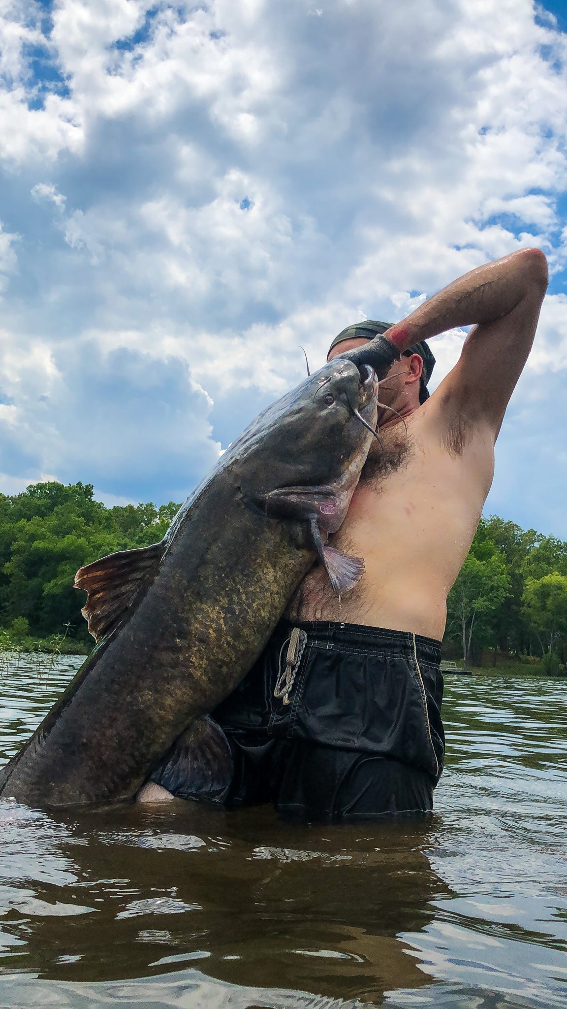 A man holds up a big flathead.