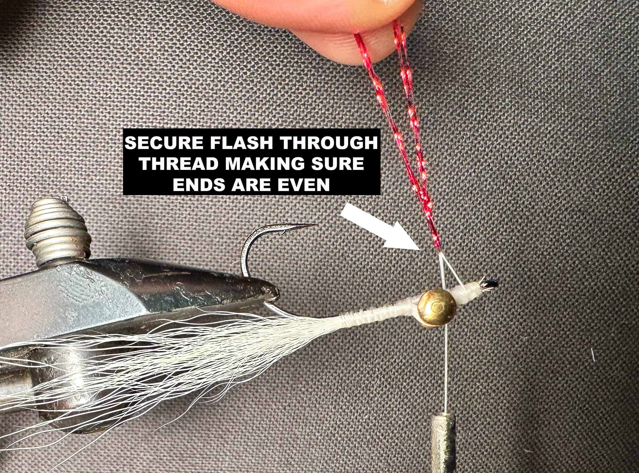 A partially-tied Clouser fly in a vise with instructions for applying flash.