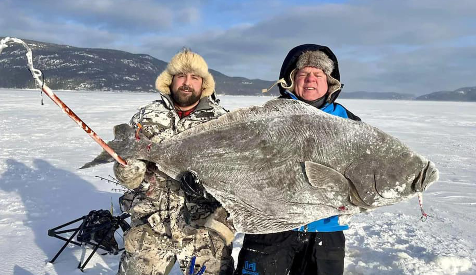 Two anglers from Quebec pose with a giant Atlantic halibut they caught through the ice.