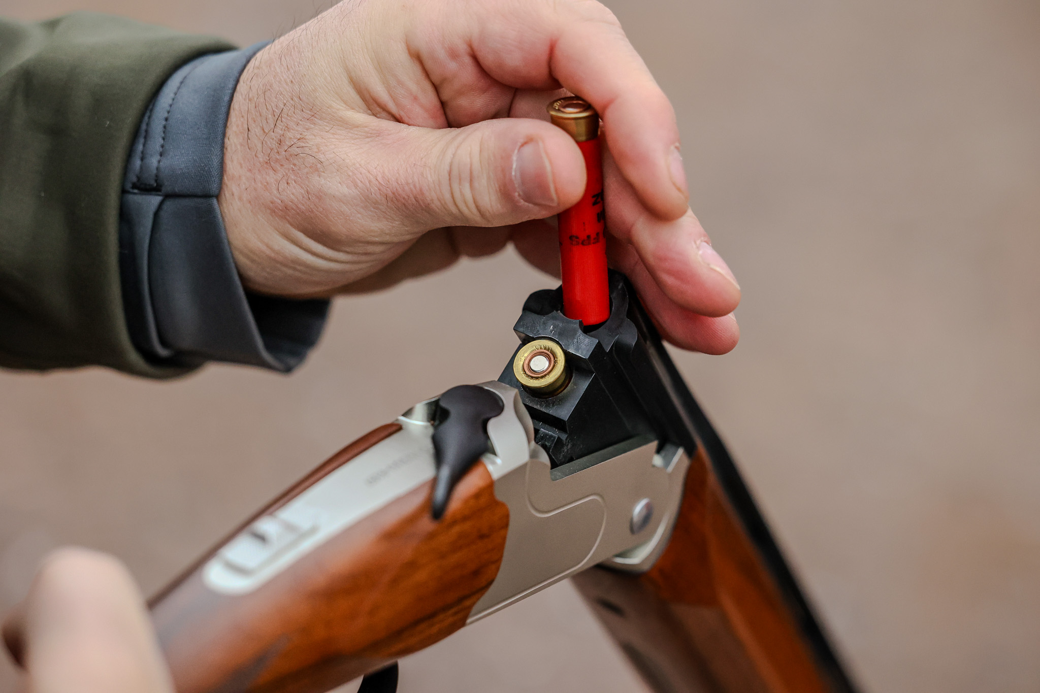 A hand loads a .410 shotgun shell into the Stevens 555 Sporting.