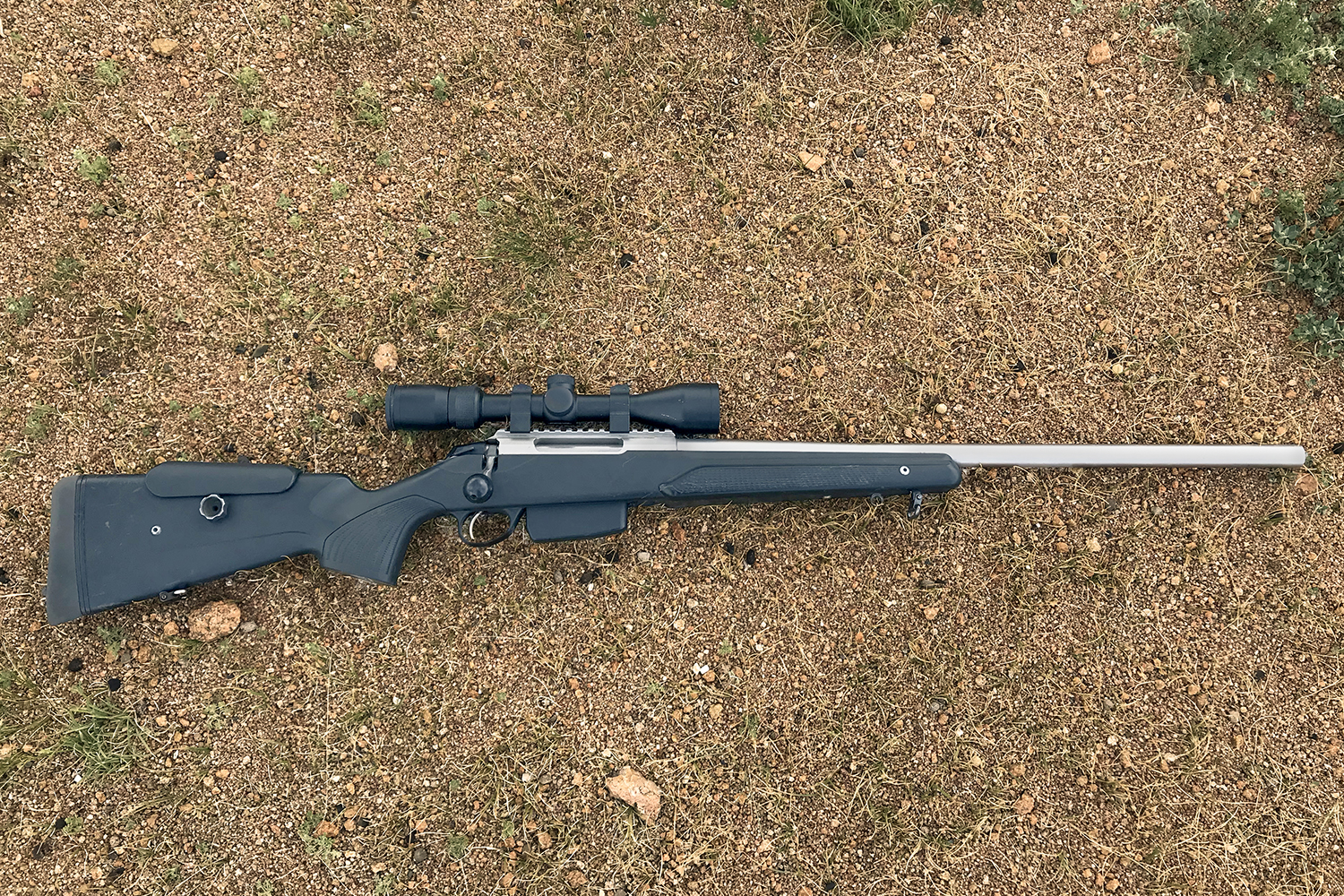 Rifle with riflescope on ground