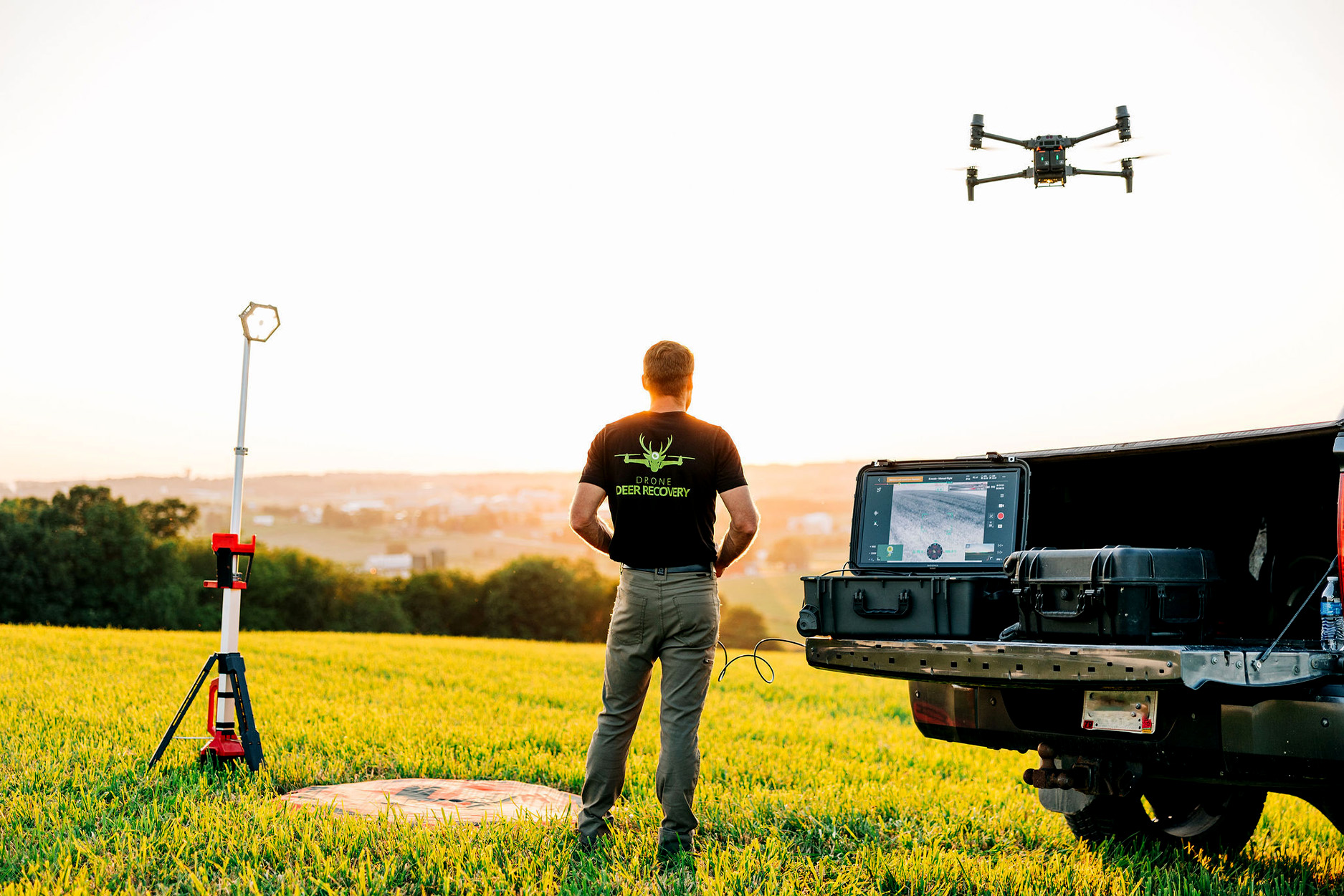 A drone pilot sends up a drone from his truck.