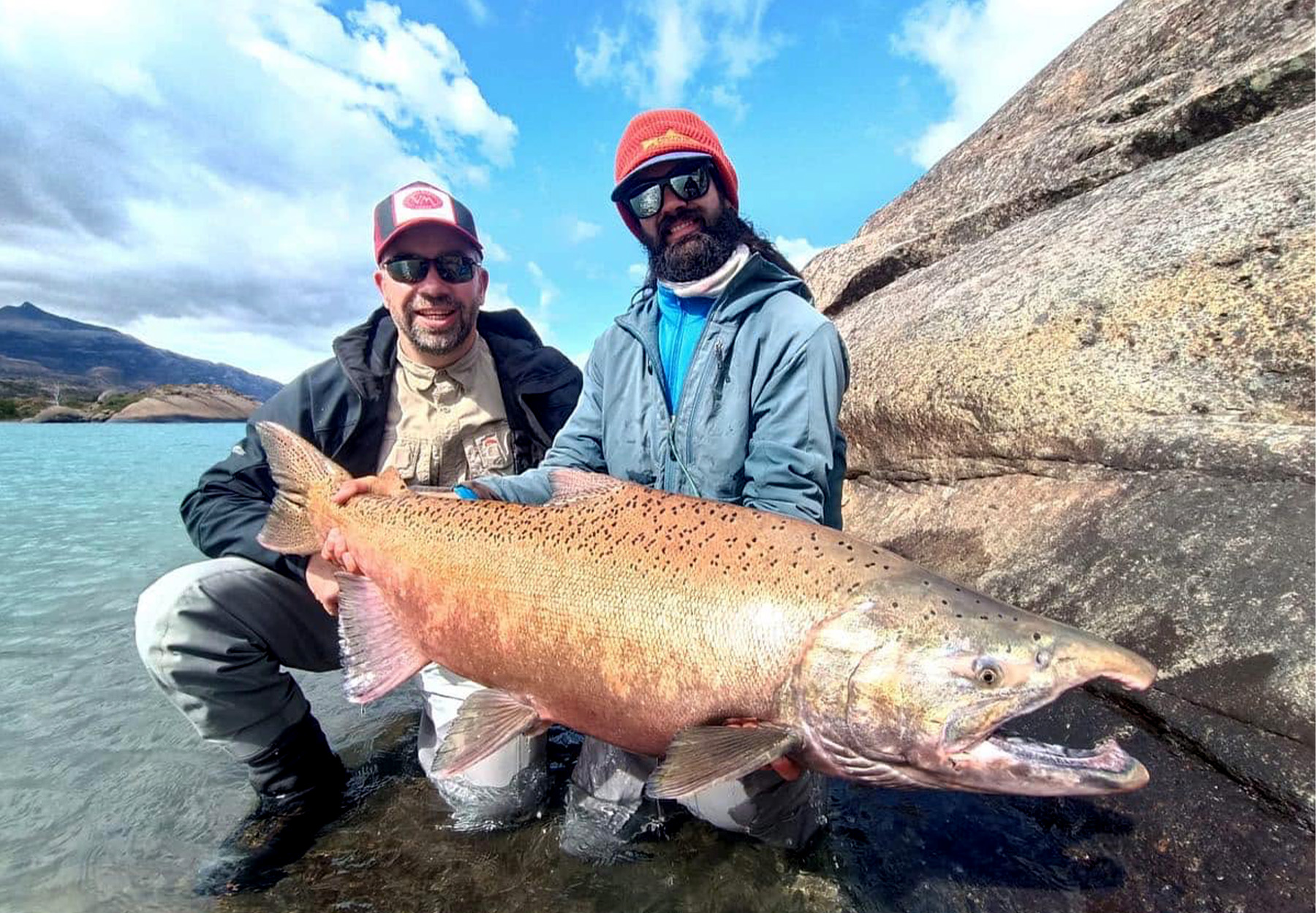 Two anglers hold up giant king salmon caught in Argentina.