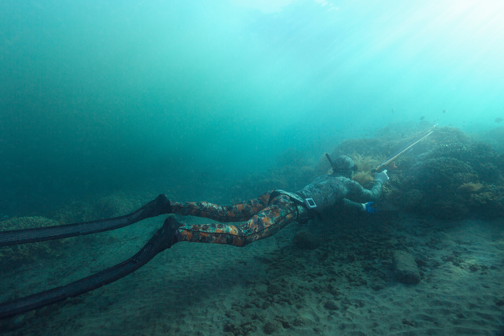 A camo-clad spearfisherman waits for a fish to swim by.