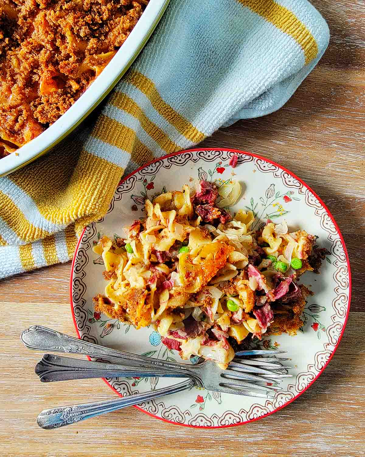 A plate of corned beef casserole next to the whole dish of it, 